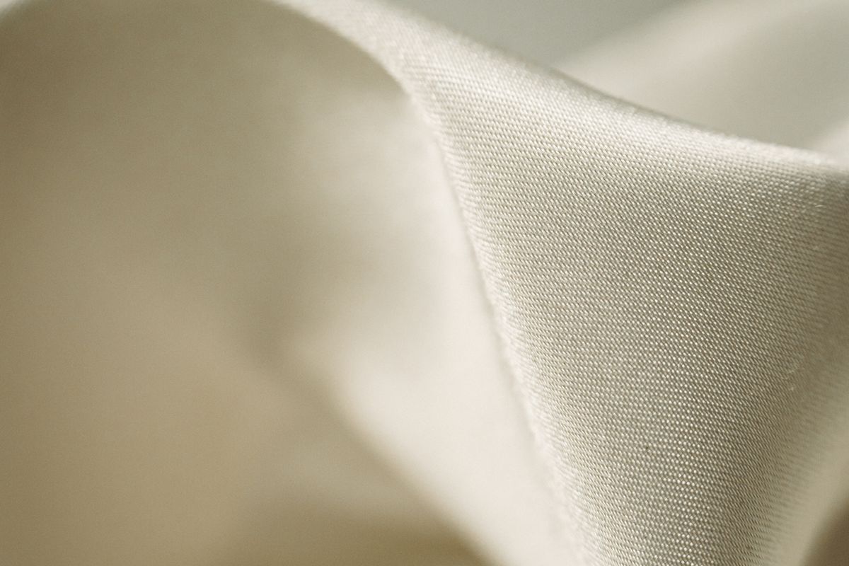 Cream lyocell-style weave curving in a smooth fold