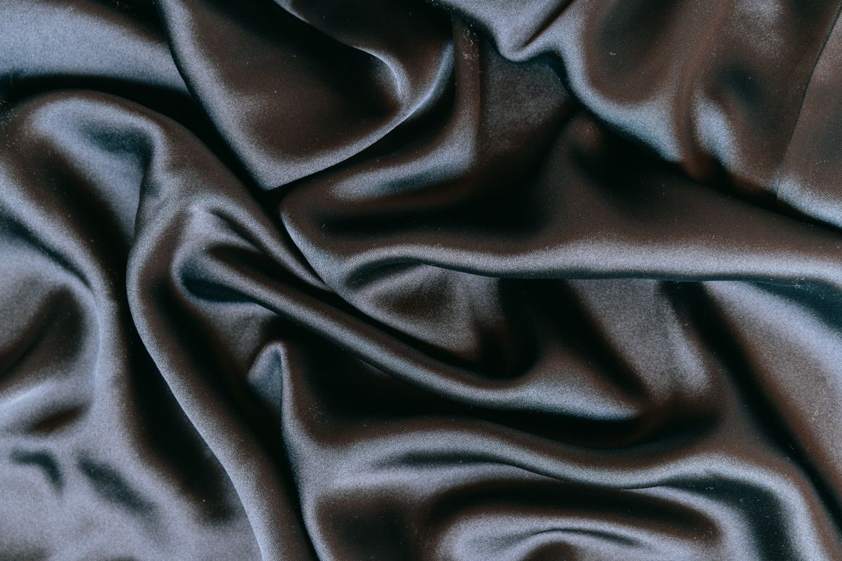 Dark silk satin falling in smooth, light-catching folds